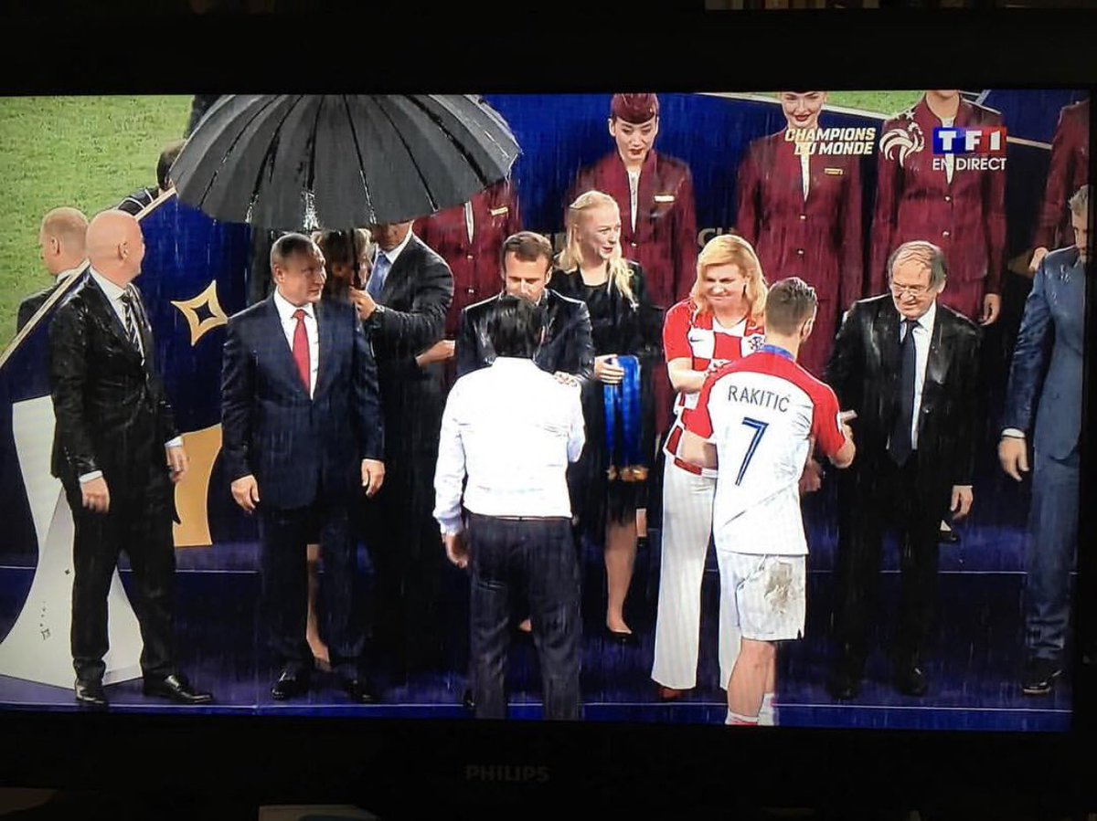 Putin, a perfect host. Next to him are leaders of France and Croatia under torrential rain